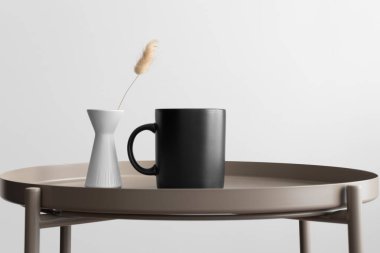 Bej masasında lagurus süslemesi olan siyah kupa..