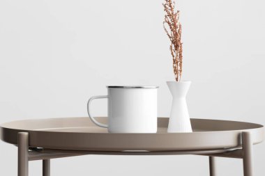 Bej masasında kuru bir çiçek süslemesi olan Enamel kupası..