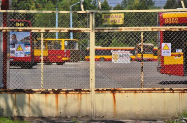 Warsaw city bus depot old rusty fence yellow red buses parked in a row