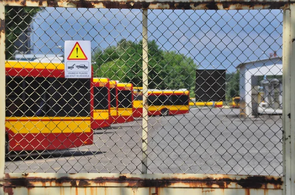 Warsaw city bus depot old rusty fence yellow red buses parked in a row
