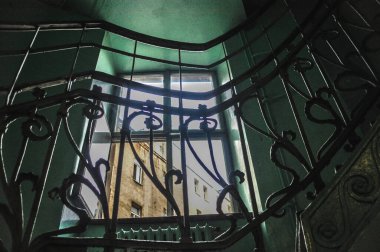Penceresi olan bir apartmanın içi, dekoratif metal parmaklıklı yeşil merdivenler terk edilmiş bir bina.