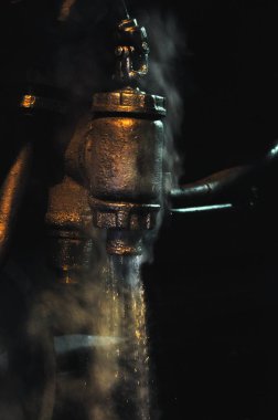 Buhar treninin buharından gelen su, karanlıkta lokomotif, loş fener ışığı.