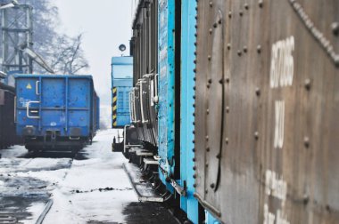 Mavi ve siyah tren vagonları kışın tren yolu kenarında durur.