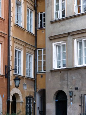 Varşova Polonya 'nın eski kasabasının arka sokağındaki renkli apartmanlar Avrupa' da beyaz pencereler geziyor