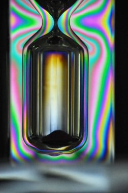 Renkli bir gökkuşağı kum saati siyah bir arkaplan ile zamanı ölçüyor