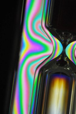 Renkli bir gökkuşağı kum saati siyah bir arkaplan ile zamanı ölçüyor