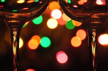 Suyla dolu şeffaf şarap kadehleri, arka plandaki ağaçta renkli Noel ışıkları.