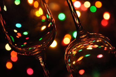 Suyla dolu şeffaf şarap kadehleri, arka plandaki ağaçta renkli Noel ışıkları.