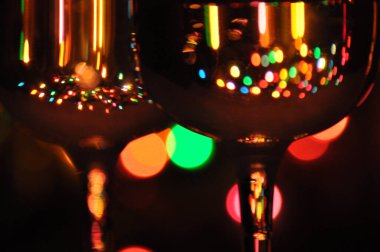 Suyla dolu şeffaf şarap kadehleri, arka plandaki ağaçta renkli Noel ışıkları.