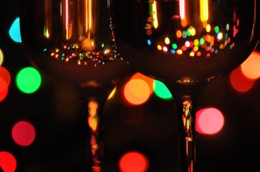 Suyla dolu şeffaf şarap kadehleri, arka plandaki ağaçta renkli Noel ışıkları.