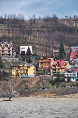 Residential houses on a hillside above a cold, rushing river Dunajec clipart