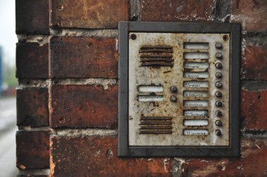 Old rusty intercom with buttons on a red brick wall of a building old town clipart