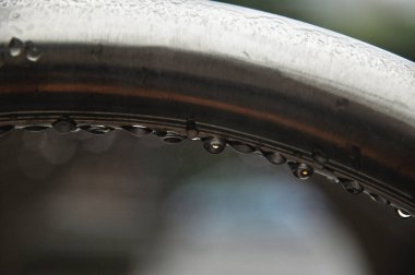 Çemberli ıslak metal çerçeve yapısı, bisiklet rafında yağmur damlaları.