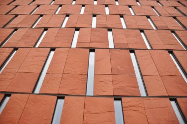 Modern bir binanın dar pencereli kırmızı tuğla cephesi, modern mimari