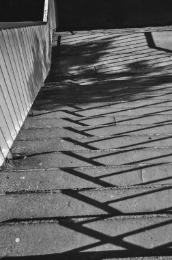 Merdivenlerin tek renkli fotoğrafı, merdivenlerden dökülen gölgelerin yakın çekimi siyah ve beyaz.