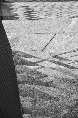 Merdivenlerin tek renkli fotoğrafı, merdivenlerden dökülen gölgelerin yakın çekimi siyah ve beyaz.