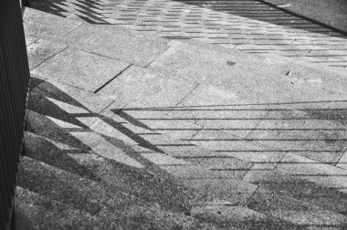 Merdivenlerin tek renkli fotoğrafı, merdivenlerden dökülen gölgelerin yakın çekimi siyah ve beyaz.