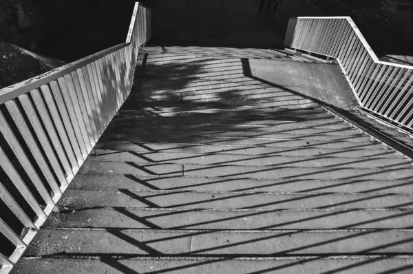 Merdivenlerin tek renkli fotoğrafı, merdivenlerden dökülen gölgelerin yakın çekimi siyah ve beyaz.