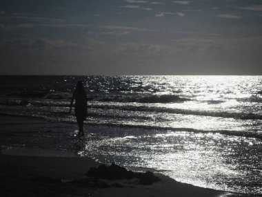 Güneş batarken Baltık Denizi kıyısında hafif bulutlu ve hafif dalgalı bir Polonya plajı.