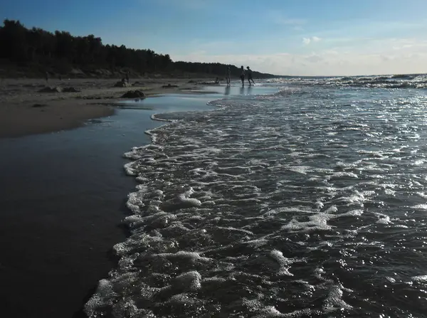Güneş batarken Baltık Denizi kıyısında hafif bulutlu ve hafif dalgalı bir Polonya plajı.
