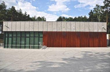 Modern, tek katlı, düz çatılı, beton ve camdan yapılmış, büyük cam pencereli bir bina.