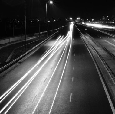 Bu büyüleyici gece fotoğrafı, hareket eden araçları canlı ışık çizgilerine dönüştürmek için uzun bir pozlama tekniği kullanır. Görüntü, kırmızı farlar ve Dyna yaratan beyaz farlarla otoyolda iki yöne giden arabaları yakalıyor.