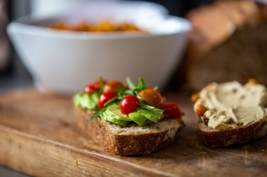 Yakın plan sağlıklı roket, avokado, humus ve domates ekmeği, sığ bir tarla derinliği