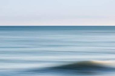 A view out over the ocean with intentional camera movement, and a clear sky overhead