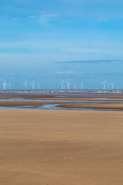 Merseyside 'daki Formby' de kıyı rüzgârı çiftliği olan alçak gelgitte kumlu bir sahil manzarası.