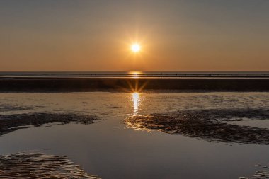 Güneşin suya yansıdığı, Formby plajında huzurlu bir gün batımı.