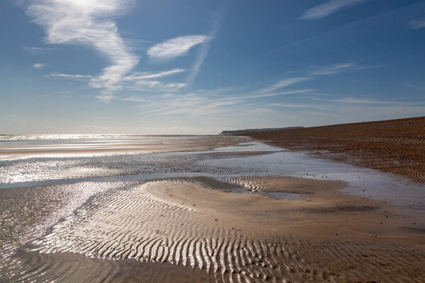 The sandy beach at Winchelsea in Sussex, with a blue sky overhead