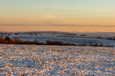 Sussex 'teki Ditchling Beacon' da kış manzarası karla kaplı tarlalarda parlayan günbatımı gökyüzü