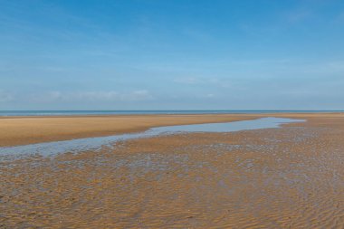 Formby Sahili 'nde dalgalar alçak, tepemizde mavi bir gökyüzü var.