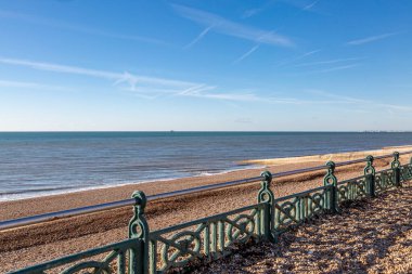 Güneşli bir kış gününde Brighton plajı boyunca çakıl taşları gezinti güvertesine vurmuştu.