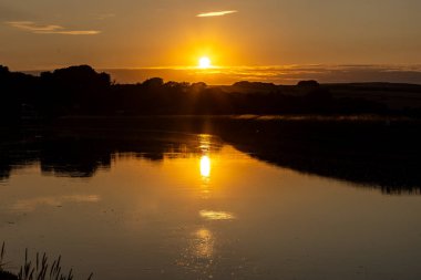 Ouse Nehri üzerinde, Sussex 'teki Piddinghoe yakınlarında huzurlu bir gün batımı.
