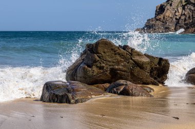 Güneşli bir yaz gününde Cornwall 'daki Portheras Koyu' na dalgalar çarpıyor.