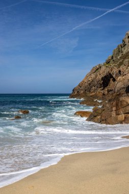 Cornish sahilindeki Portheras Koyu 'ndaki kumlu sahil ve engebeli uçurumlar