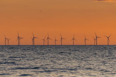 Sussex açıklarında okyanusta rüzgar türbinleri, dramatik bir günbatımı ile