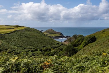 Yeşil tepelerin üzerinden Cornwall Burnu 'na ve okyanusa doğru bakan mavi bir gökyüzü.