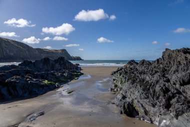 Traeth Llyfn 'deki kum ve kaya oluşumlarına bakıyorum, güneşli bir günde tepemizde mavi bir gökyüzü