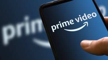 Arka planda rampa rengi olan cep telefonu ekranında asal video mavi logosu. Akıllı telefon ekranında el ele tutuşan filmler ve TV dizisi ikonu. İtalya, Milan, 24-01-22