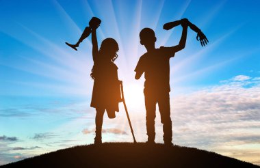 Two children silhouetted against a stunning sunset, proudly holding their prosthetic limbs. This photo highlights the strength and determination of young individuals overcoming physical challenges clipart