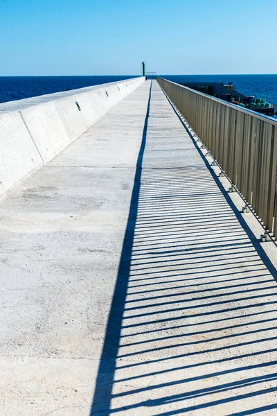 アメトラ タラゴナ カタルーニャ スペインのセメント表面に平行線の影を持つ防波堤上の遊歩道の消失点 — ストック写真