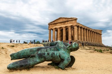 Agrigento, Italy - May 8, 2023: Temple of Concordia and the Icarus bronze statue in the Valle dei Templi or Valley of the Temples with people around in Agrigento, Sicily, Italy clipart