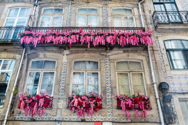 Portekiz 'in eski Porto veya Oporto kasabasında asılı duran fayanslar ve çiçeklerle süslenmiş eski klasik bir binanın cephesi.