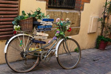 Collioure, Fransa - 17 Haziran 2024: Fransa 'nın Collioure veya Cotlliure kasabasındaki bir balıkçı köyünde üzerinde çiçek ve yön işaretleri bulunan bisiklet