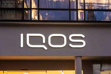 Munich, Germany - April 3, 2025: Sign of the Iqos shop with a line of heated tobacco products of Philip Morris International or PMI in Kaufingerstrabe, shopping street in Munich, Bavaria, Germany 