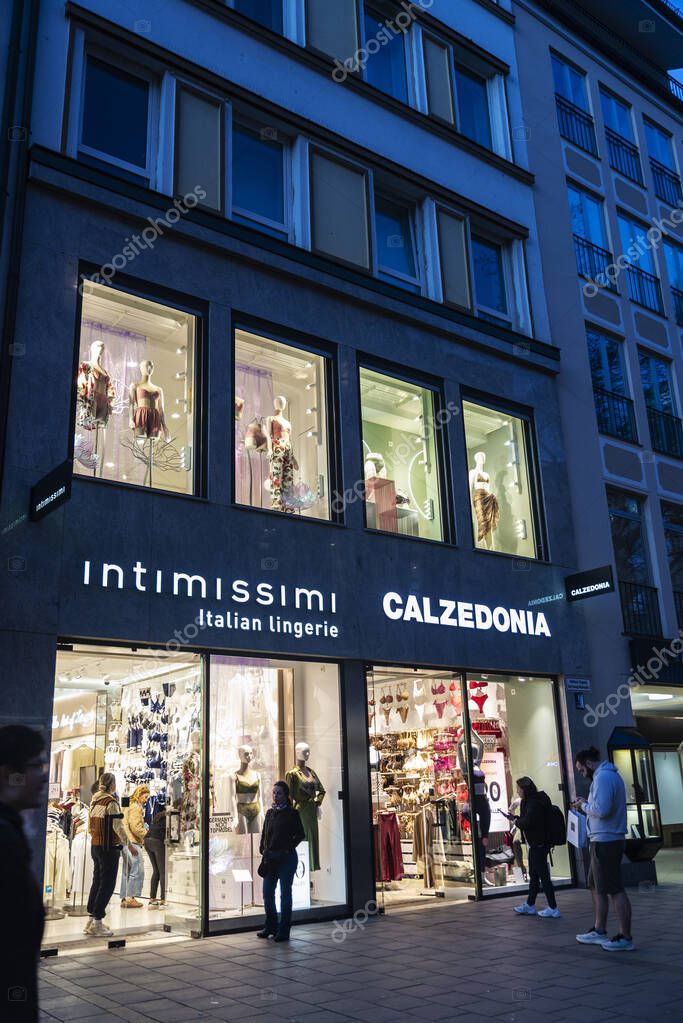 Munich, Germany - April 3, 2025: Illuminated sign of a Intimissimi and Calzedonia clothing store at night in Kaufingerstrabe, a shopping street in Munich, Germany