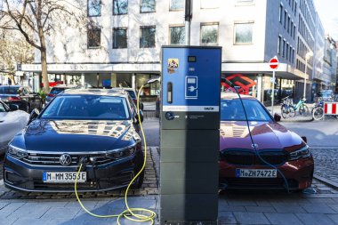 Münih, Almanya - 4 Nisan 2025: Almanya 'nın Münih kentindeki bir caddede şarj noktasında elektrikli araçlar şarj ediliyor