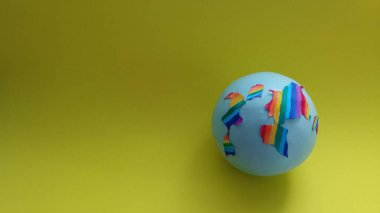 dünya konsepti. Yeşil arka planda bir dünya. Küre, sarı bir zemin üzerinde gökkuşağı renkleriyle boyanmıştır ve metin için yer vardır. Dünya 'nın çeşitliliği. LGBT konuları. Seks eğitimi. Hoşgörü konusu